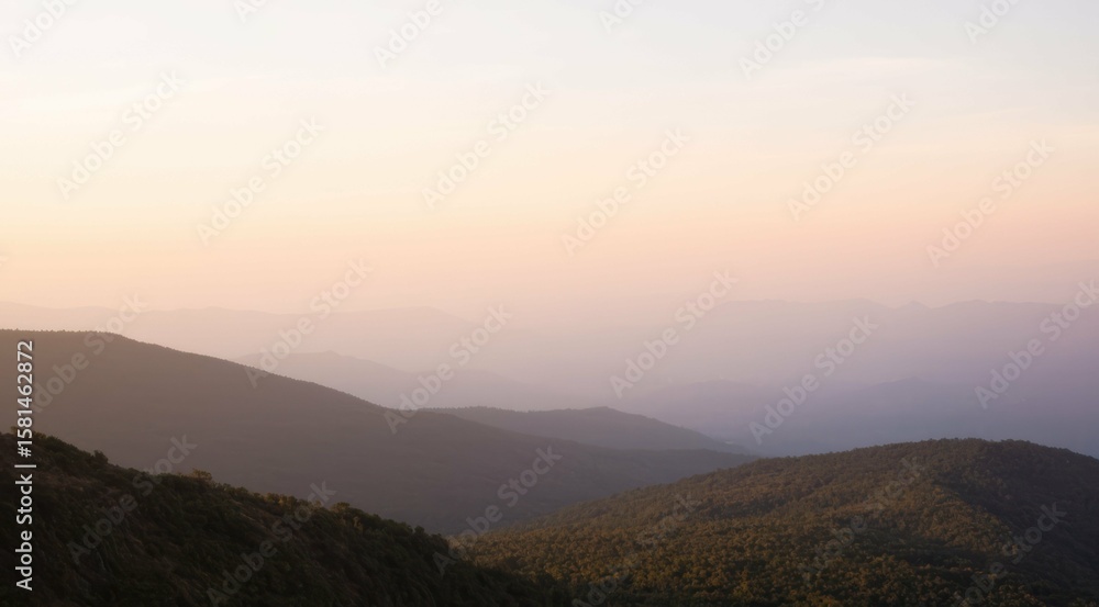 Fototapeta premium Layered mountain range at twilight with soft, pastel light