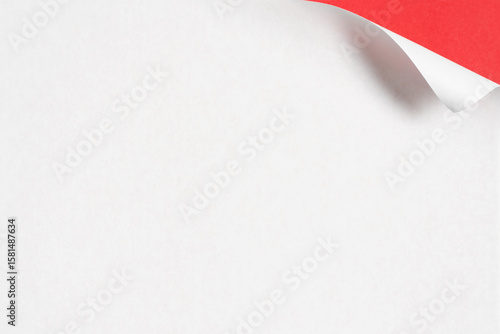 Fotografie Minimalist image of a white paper with its top corner curled to reveal a bright red back