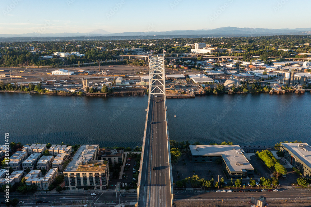 Obraz premium Aerial drone picture of Portland’s Fremont Bridge at sunset, the Willamette River, Downtown Portland, industrial area, and Mt. Hood in the background, with clear blue summer sky