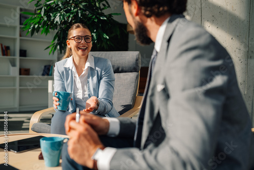 Papier peint Businesswoman holding coffee mug talking to businessman in office lounge area