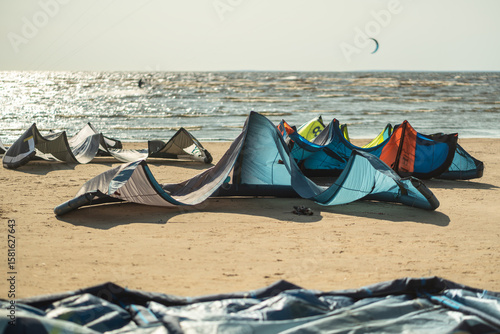 Kite surfing at beach by sea with colorful inflatable kites waiting for competition. Surfers preparing in background during summer, tourism and travel active recreation, sports leisure activity