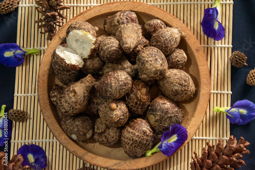 Organic farm‑to‑table produce in flat lay view, freshly steamed taro roots styled with blue flowers and pine cones.