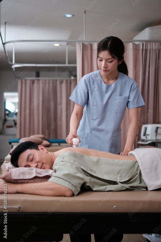 Obraz premium Female physical therapist doctor treat male Asian patient with gel ultrasound for back pain relief for muscle recovery, passive medical therapy at spa clinic, and wellness massaging healthcare.