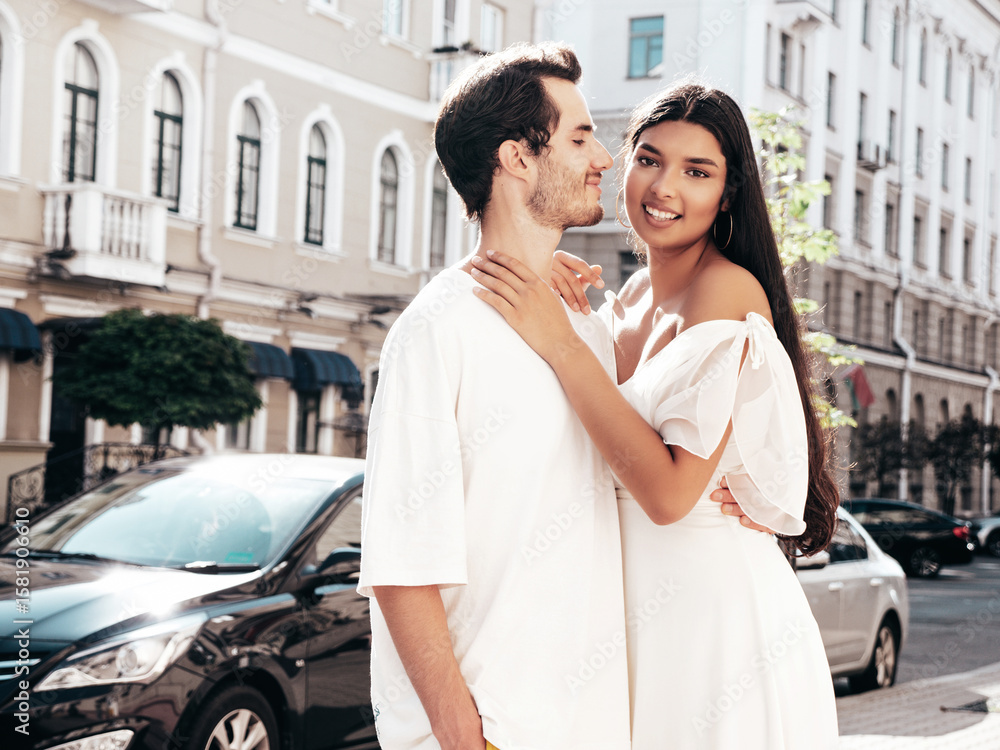 Fototapeta premium Smiling beautiful woman and her handsome boyfriend. Happy cheerful family. Sexy couple posing in the street at sunrise. During romantic date at sunny summer day outdoors. Looking at each other