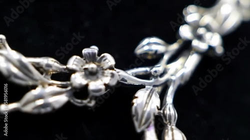 Elegant silver floral necklace on black background, macro jewelry detail