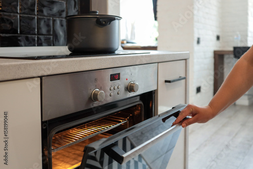 Tableau sur toile Close-up of a hand opening a hot oven in a modern kitchen