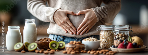 Woman in Cozy Sweater Making Heart Shape with Hands on Stomach Surrounded by Healthy Foods Including Milk, Nuts, Fruits, and Oats