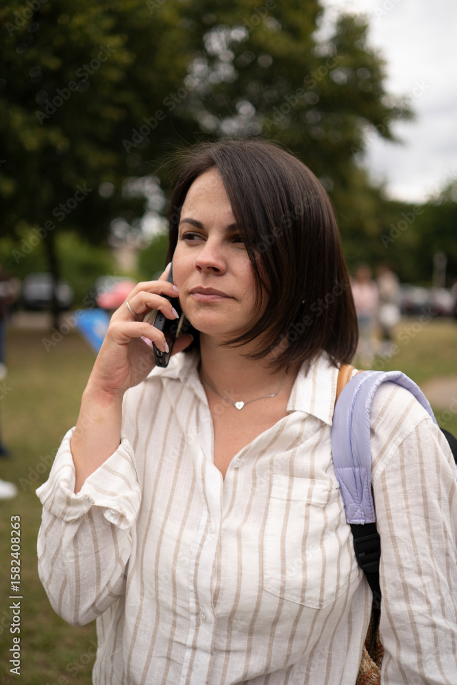Vertical portrait of serious woman in blouse on phone in a busy street. Concept: urban contrast, inner focus, modern lifestyle, connection in motion. Vertical portrait of serious woman in blouse on phone in a busy street. Concept: urban contrast, inner focus, modern lifestyle, connection in motion.