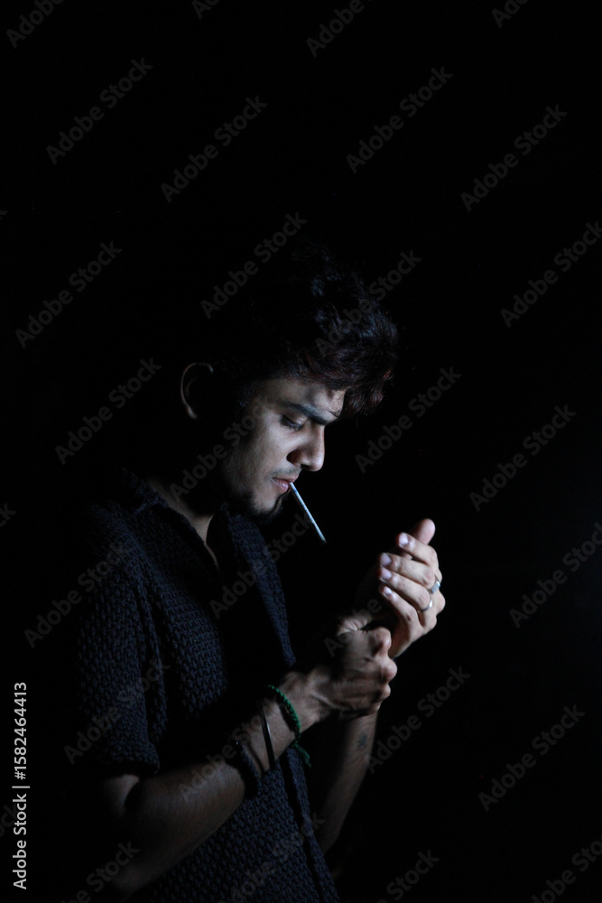 Obraz premium Mysterious Man Smoking in Dim Light – Stylish Dark Portrait on Black Background