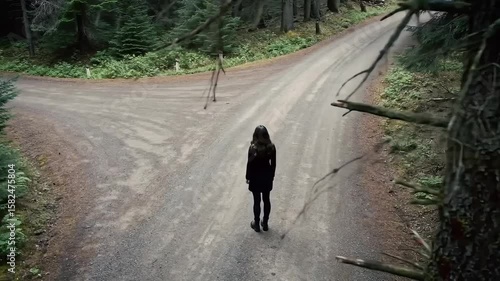 A solitary woman stands at a crossroads on a path through a serene forest, facing a symbolic choice in the wilderness.