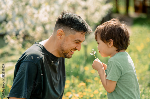 Father and son enjoying a sunny day with dandelions in a field