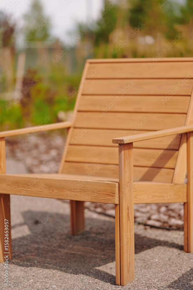 Fototapeta premium outdoor wooden chair in sunlight surrounded by garden greenery, ideal for backyard relaxation and leisure. sturdy build with natural finish captures serene outdoors vibe