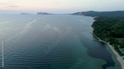 Wallpaper Mural Breathtaking aerial vista showcases a tranquil ocean meeting a lush green coastline with majestic distant land formations under a peaceful sky Torontodigital.ca