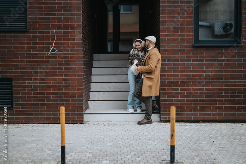 Wallpaper Mural A young couple enjoys a relaxed moment outside on a city street. They lean against a modern brick building while talking and laughing, capturing a candid urban lifestyle scene. Torontodigital.ca