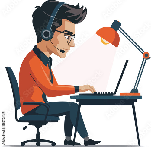 Young man in headset working on laptop at desk with desk lamp