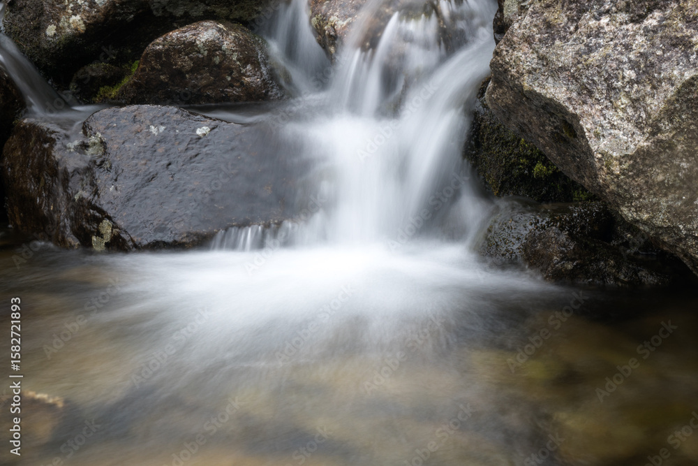 Obraz premium Clear water flowing in a mountain stream, photo taken with a long exposure effect. 