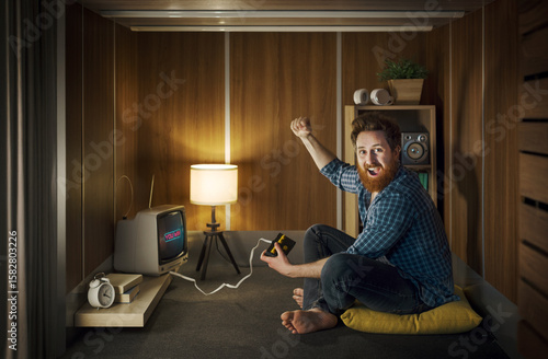 Foto Cheerful man playing video games in a tiny living room
