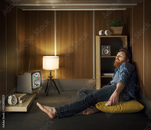 Photography Man in a small room sleeping with the TV on