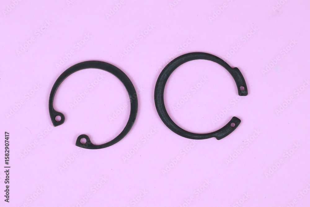 Obraz premium Top view two black Circlip or ring retaining isolated on pink background.