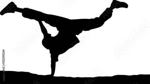 Silhouette of a breakdancer performing a handstand with legs split in the air on a ground surface