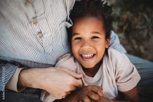 Portrait of black multiracial 5yo boy laughing on dad lap