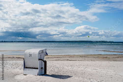 A single white beach chair stands on a beach in the Kiel Fjord in Germany.
