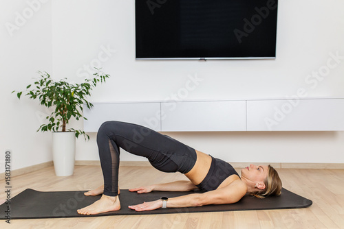 Woman practicing glute bridge yoga pose at home