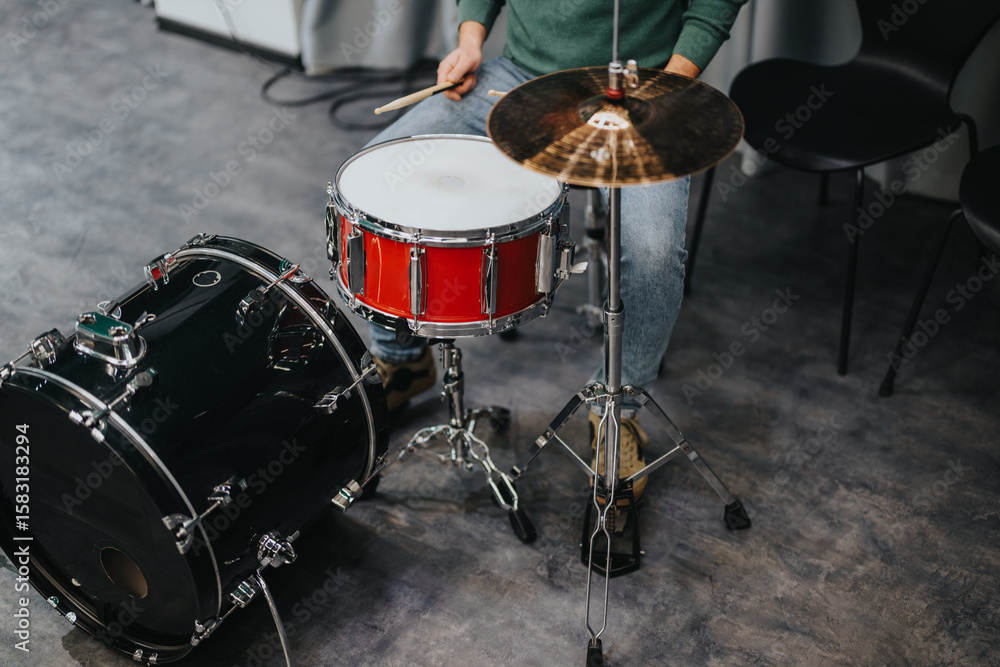 Obraz premium A drummer is practicing on a drum kit in a music studio. The setting is informal, focusing on the artistry and dedication involved in refining drum skills.