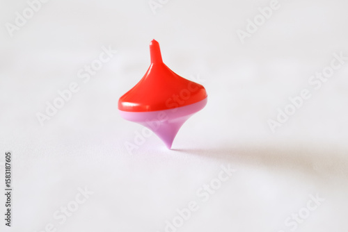 Schilderij op canvas Close-up of a pink and red spinning top spinning on a wooden table