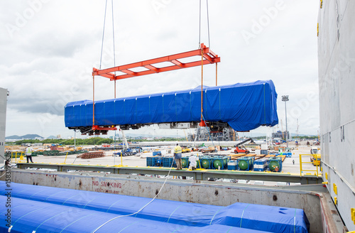 Unloading operation of project  cargo with port heavy lift cranes A crane on a large cargo ship docks loading a new passenger train at Laem Chabang Port