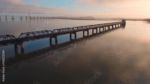 Wallpaper Mural Slow zoom in toward the old Dumbarton Railroad Bridge, with early morning light casting soft reflections across the tranquil bay. Torontodigital.ca