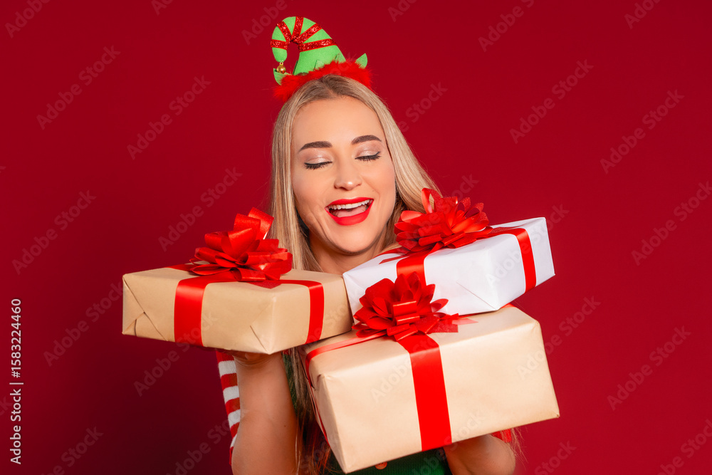 Fototapeta premium Joyful young woman celebrating with colorful wrapped gifts in a festive setting during the holiday season