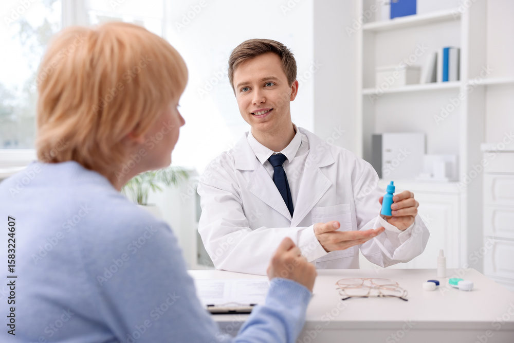 Fototapeta premium Ophthalmologist consulting senior woman at white table in clinic