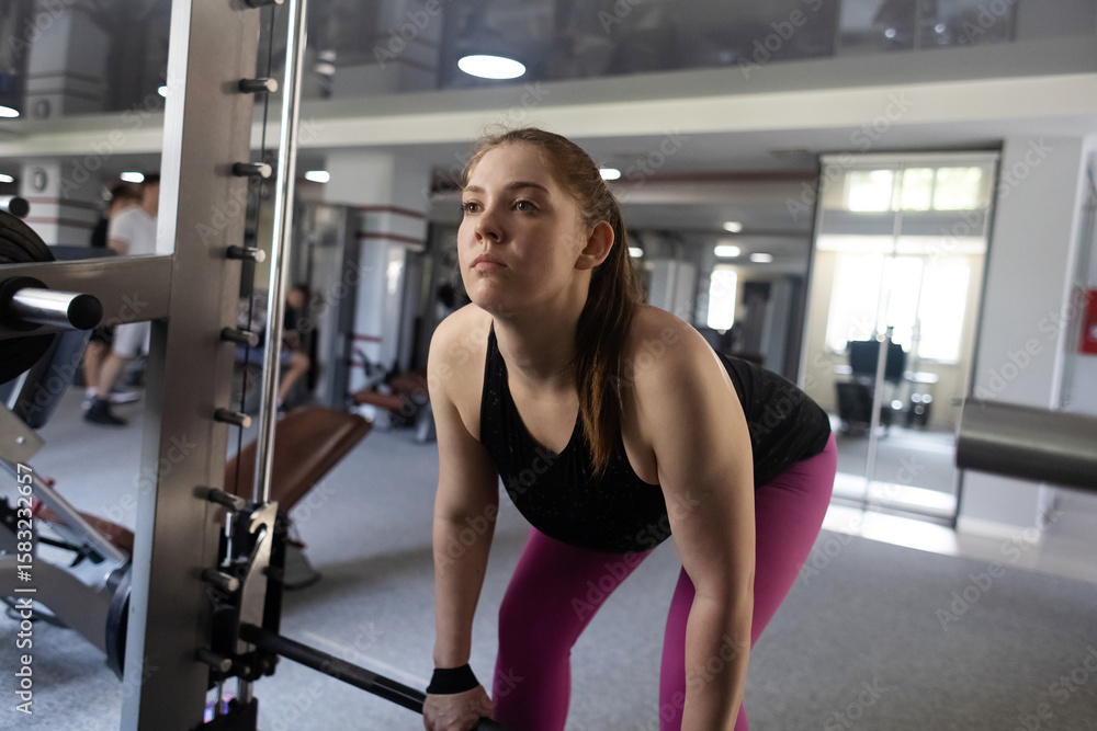 Fototapeta premium Plus size woman doing exercises on Smith Machine. Squats on a simulator with a barbell. Workout for weight loss