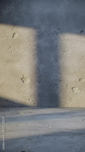 Pristine, modern, minimalist studio environment featuring a rough-textured gray concrete wall and matching floor. Static wide, slightly low-angle medium video with golden hour sunbeams casting
