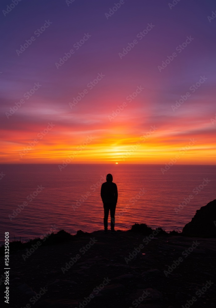 Fototapeta premium Silhouette of Person Watching Vibrant Sunset Over Ocean