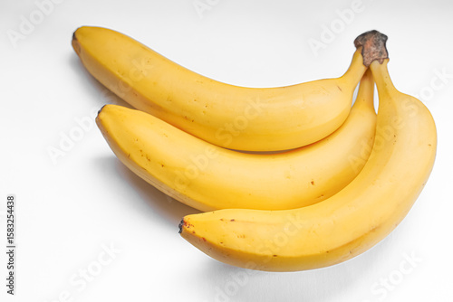 Three ripe bananas arranged on a white surface.
