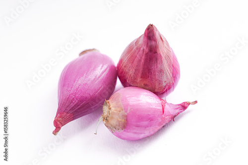 Three small, vibrant pink shallots arranged on a plain white background.