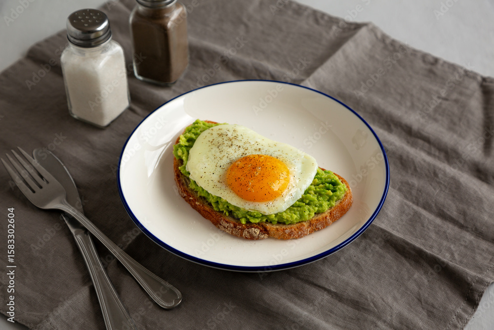Homemade Avocado Toast with Egg on a Plate, side view. Homemade Avocado Toast with Egg on a Plate, side view.