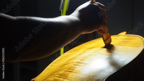 Fotografie Skilled luthier varnishing cello soundboard with precision brush, highlighting i