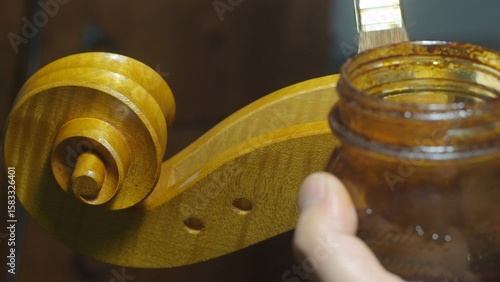 Obraz na plátně Luthier applying varnish with a brush on a cello part in a traditional workshop,