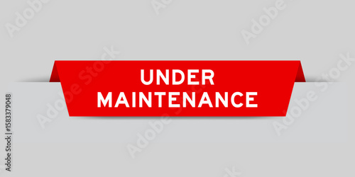 Red color inserted label with word under maintenance on gray background