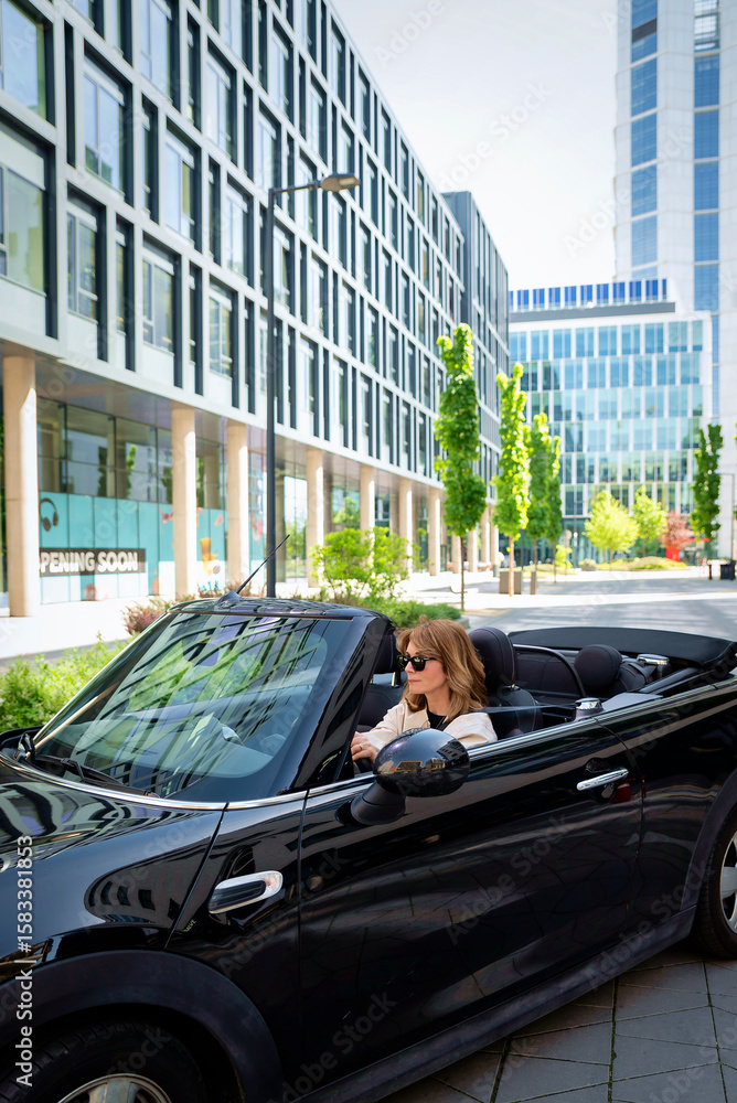 Blond haired woman driving her convertible car in the city Blond haired woman driving her convertible car in the city