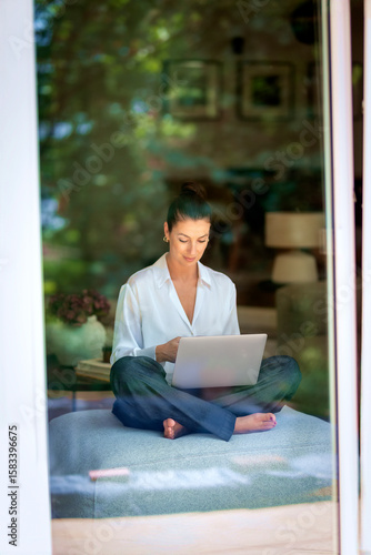 A caucasian woman photographed through the window whilesitting on a chair and using laptop Free Download A caucasian woman photographed through the window whilesitting on a chair and using laptop - GFXLoad