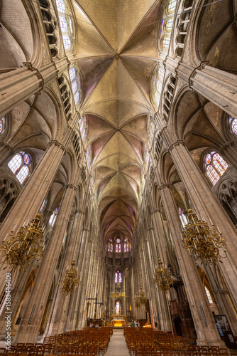 Bourges Cathedral nave showing gothic architecture, stained glass windows and chandeliers in France