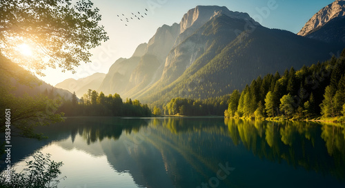 Tranquil alpine lake reflects towering peaks and a golden morning sky with birds.