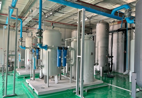  Industrial air compressor system and filtration tanks in a clean facility. Modern piping layout with pressure vessels, filters, and stainless steel components used in factory and utility infrastr