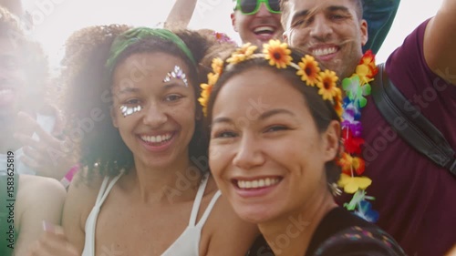 Group of young friends dancing behind barriers at music festival site posing for selfie- shot in slow motion