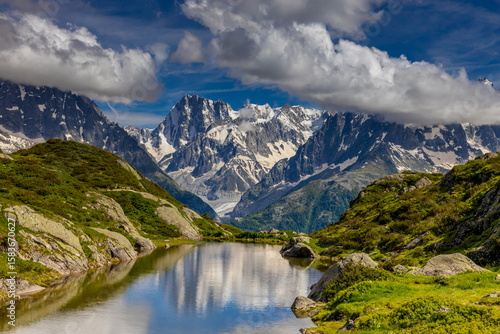 Beautiful mountain landscapes of the Alps on Tour du Montblanc hike. Green valley, snow summits and rocky peaks of Aiguilles de Chamonix and Montblanc. Summer sunny weather blue sky, trekking Alp hike