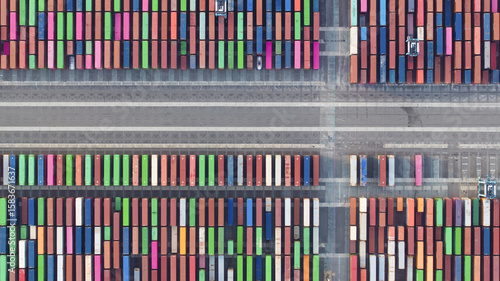 [Port of Oakland], United States - 07 April 2025: Aerial view of vibrant shipping containers lined in neat rows, their colorful surfaces creating a striking contrast against the stark gray asphalt.